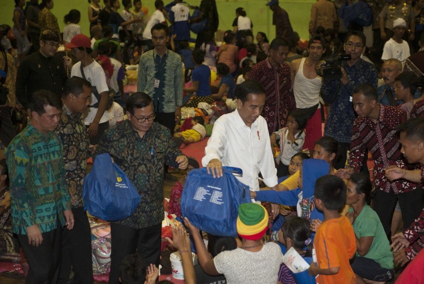 Presiden Joko Widodo (ketiga kiri) bersama Bupati Klungkung I Nyoman Suwirta (kiri) dan Mensesneg Pramono Anung (kedua kiri) memberi bantuan kepada para pengungsi Gunung Agung di GOR Suwecapura, Klungkung, Bali, Selasa (26/9).