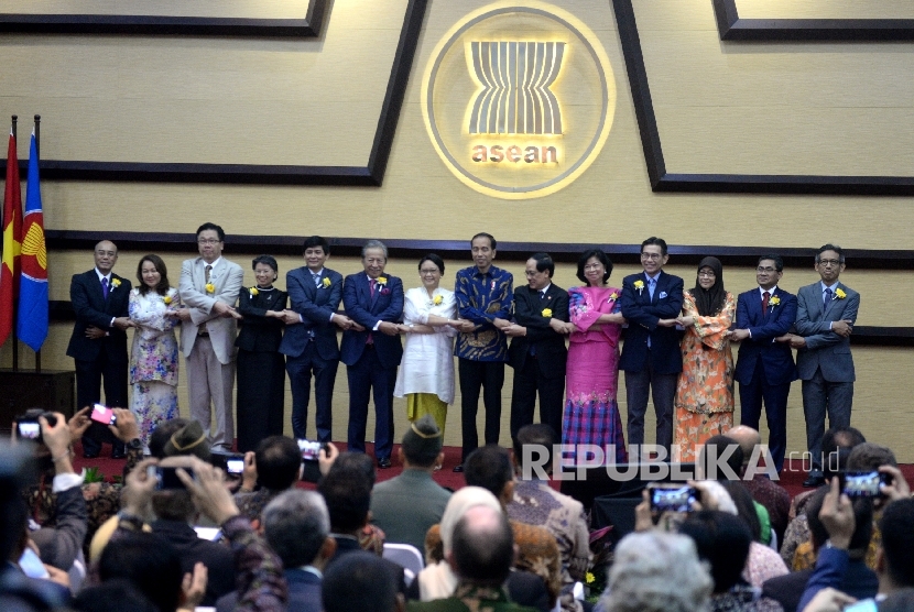 Presiden Joko Widodo (ketujuh kanan) bergandengan tangan dengan Sekjen ASEAN Le Luong Minh (keenam kanan), Menteri Luar Negeri Retno Marsudi (ketujuh kiri), dan perwakilan dari masing-masing negara anggota ASEAN berfoto bersama saat peringatan 50 tahun ASEAN di Sekretariat ASEAN, Jakarta, Jumat (11/8).