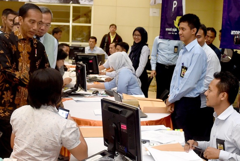 Presiden Joko Widodo (kiri) berbincang dengan petugas pajak saat melayani wajib pajak yang ikut serta dalam program Pengampunan Pajak di Kantor Pelayanan Pajak Gabungan di Jalan M.I. Ridwan Rais, Jakarta, Rabu (28/9).