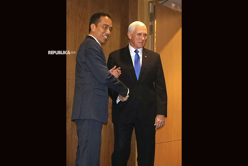 Presiden Joko Widodo (kiri) berjabat tangan dengan Wapres AS Mike Pence sebelum melakukan pertemuan bilateral di sela KTT ASEAN di Pusat Konvensi Suntec, Singapura, Rabu (14/11/2018).