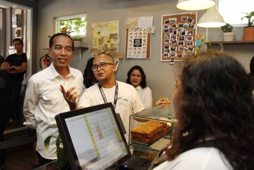Presiden Joko Widodo (kiri) bersama Ibu Negara Iriana (ketiga kiri) mendengarkan penjelasan Pemilik Tuku Kopi Andanu Prasetyo (tengah) saat meminum kopi bersama keluarga di Tuku Kopi, Jakarta, Minggu (2/7). 