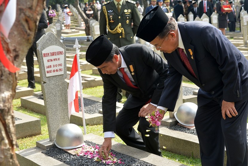 Presiden Joko Widodo (kiri) dan Wapres Jusuf Kalla (kanan) menabur bunga di makam mantan Ketua MPR Almarhum Taufiq Kiemas saat Upacara Ziarah Nasional di Taman Makam Pahlawan Nasional Utama Kalibata, Jakarta, Kamis (10/11).