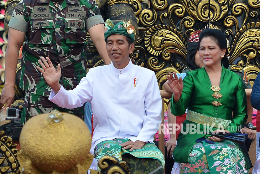 Presiden Joko Widodo (kiri) didampingi Ibu Negara Iriana Joko Widodo melambaikan tangan ketika mengikuti Pawai Pesta Kesenian Bali ke-40 di Denpasar, Bali, Sabtu (23/6).