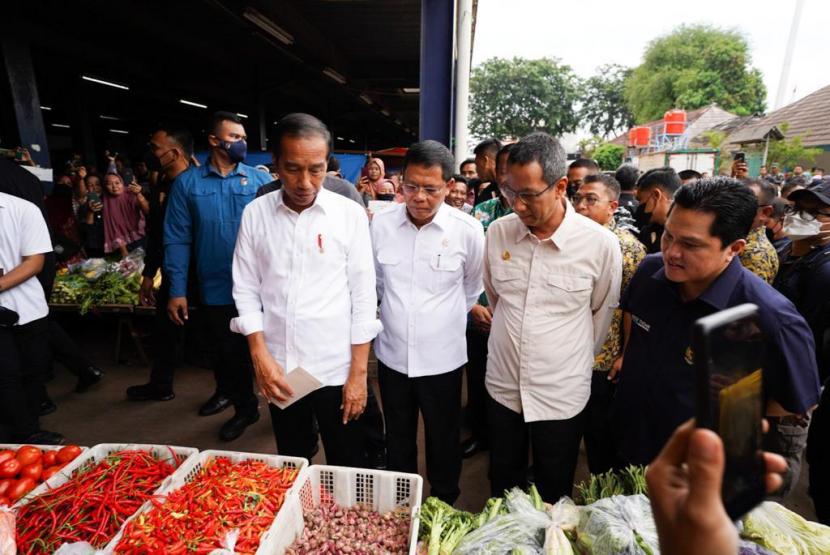 Presiden Joko Widodo (kiri) didampingi Menteri BUMN Erick Thohir (kanan) dan UKP Pengentasan Kemiskinan dan Ketahanan Pangan Muhamad Mardiono (kedua kiri) menanyakan harga sayur kepada pedagang saat mengunjungi Pasar Minggu, Jakarta, Kamis (13/4/2023).
