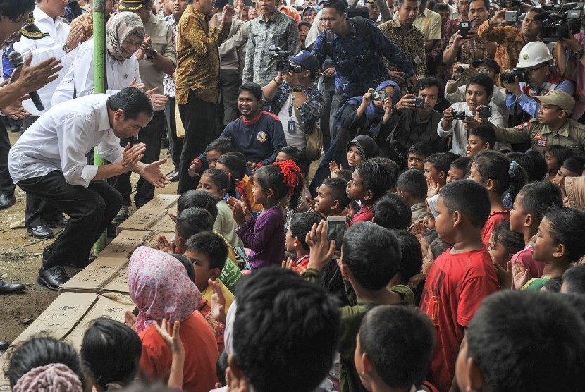 Presiden Joko Widodo (kiri) didampingi Menteri Kesehatan Nila F. Moeloek (kedua kiri) bernyanyi bersama anak-anak korban gempa di halaman Masjid Atta Darut, Pidie Jaya, Aceh, Jumat (9/12).