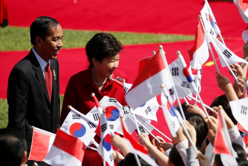 Presiden Joko Widodo (kiri) didampingi Presiden Korea Selatan Park Geun-hye menyapa para penyambut yang membawa bendera Korea Selatan dan bendera Indonesia di istana kepresidenan di Blue House di Seoul, South Korea, Senin (16/5). 