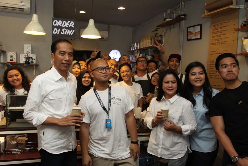 Presiden Joko Widodo (kiri), Ibu Negara Iriana (ketiga kanan) dan dua anak Kaesang Pangarep (kanan) dan Kahiyang Ayu (kedua kanan) didampingi Pemilik Tuku Kopi Andanu Prasetyo (kedua kiri) berfoto bersama saat meminum kopi di Tuku Kopi, Jakarta, Minggu (2/7). 