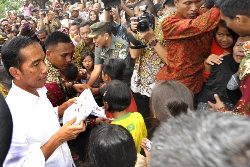 Presiden Joko Widodo (kiri) membagikan santunan kepada warga kurang mampu di Sempu, Cipare, Serang, Banten, Kamis (30/6). 