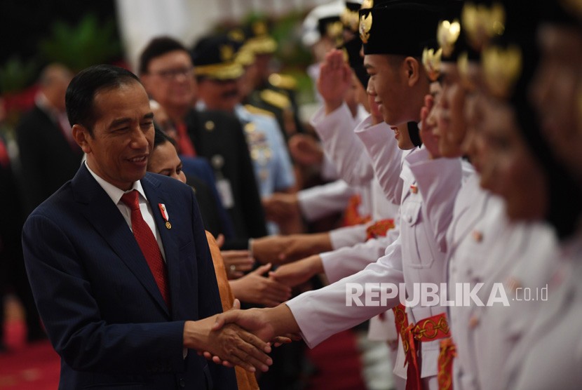 Presiden Joko Widodo (kiri) memberi ucapan selamat kepada anggota Pasukan Pengibar Bendera Pusaka (Paskibraka) usai upacara pengukuhan di Istana Negara, Jakarta, Kamis (15/8/2019).