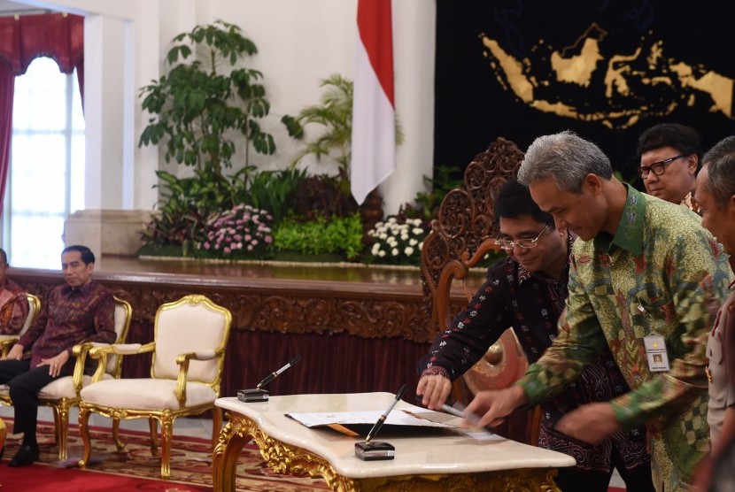 Presiden Joko Widodo (kiri) menyaksikan penandatanganan kerja sama fasilitas Kemudahan Investasi Langsung Konstruksi (KLIK) oleh Gubernur Jawa Tengah Ganjar Pranowo di Istana Negara, Jakarta, Senin (22/2). 