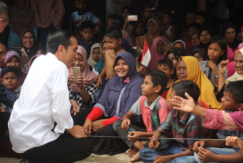 Presiden Joko Widodo (kiri) menyapa anak-anak korban gempa saat mengunjungi tempat pengungsian sementara di Desa Meurah Dua, Kecamatan Meureudu, Pidie Jaya, Aceh, Jumat (9/12). 