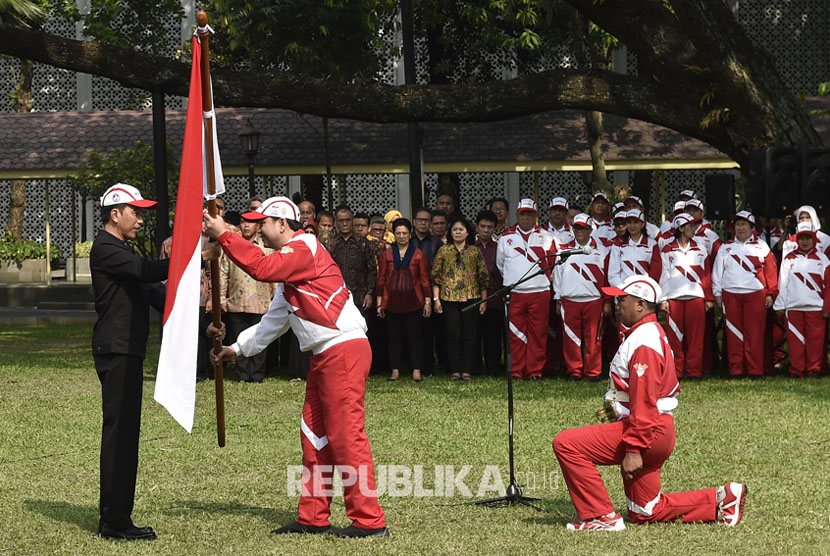 Presiden Joko Widodo (kiri) menyerahkan bendera Merah Putih kepada Ketua Kontingen Indonesia SEA Games XXIX Malaysia Aziz Syamsuddin (kedua kiri) saat upacara pelepasan di halaman Kompleks Istana Kepresidenan, Jakarta, Senin (7/8).