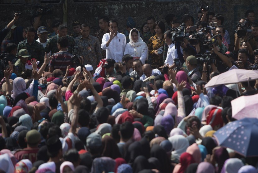 Presiden Joko Widodo (kiri tengah) melambaikan tangan didampingi Ibu Negara Iriana Joko Widodo (kanan tengah) saat membagikan sembako kepada warga di Kampung Caringin, Kabupaten Bogor, Jawa Barat, Rabu (21/6). 