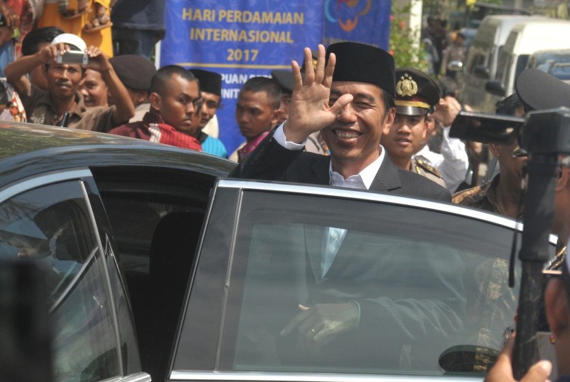 Presiden Joko Widodo melambaikan tangan ke arah warga seusai melakukan kunjungan di Pondok Pesantren An-Nuqoyah, Guluk-Guluk, Sumenep, Jawa Timur, Ahad (8/10).