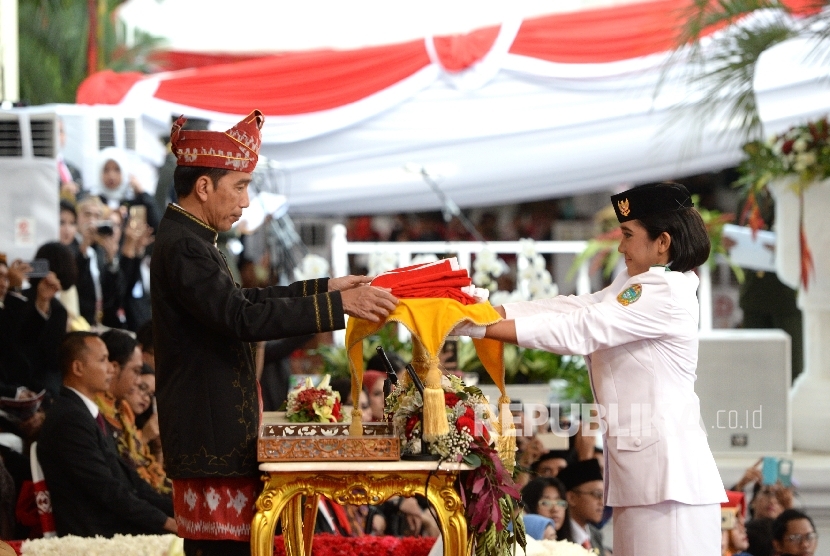   Presiden Joko Widodo menerima bendera pusaka merah putih dari anggota Paskibraka Ruth Cheliine Eglesya Purba pada Upacara Hari Kemerdekaan ke-72 di Istana Merdeka, Jakarta, Kamis (17/8). P