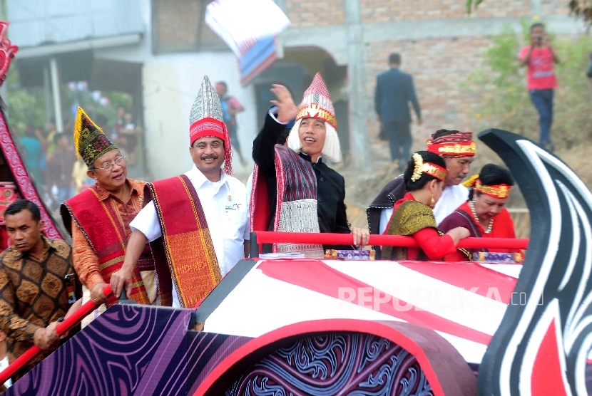 Presiden Joko Widodo mengenakan pakaian Adat Batak bersama Menteri Pariwisata Arief Yahya menyapa warga Balige saat Karnaval Kemerdekaan Pesona Danau Toba, Balige, Sumatra Utara, Ahad (22/8). (Republika/ Agung Supriyanto)