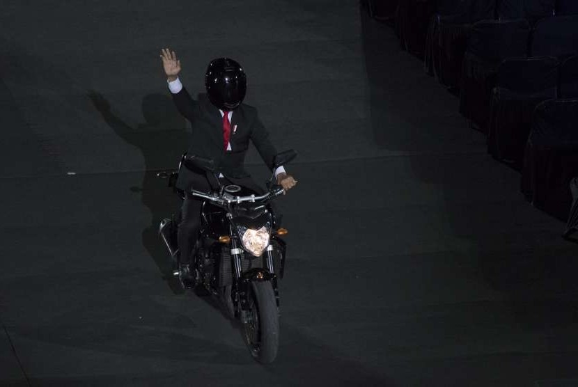 Presiden Joko Widodo mengendarai motor sambil melambaikan tangan saat pembukaan Asian Games ke-18 tahun 2018 di Stadion Utama Gelora Bung Karno, Jakarta, Sabtu (18/8).
