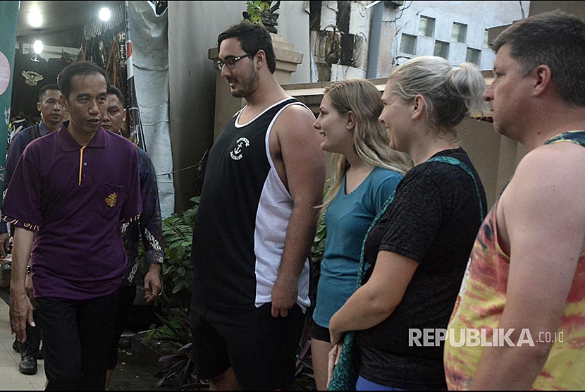 Presiden Joko Widodo menyapa wisatawan mancanegara saat mengunjungi objek wisata Pantai Kuta, Bali, Jumat (22/12). Kunjungan Presiden Jokowi tersebut untuk mengetahui kondisi pariwisata di kawasan Kuta sebelum memimpin rapat terbatas terkait penanganan dampak erupsi Gunung Agung pada sektor pariwisata Bali.