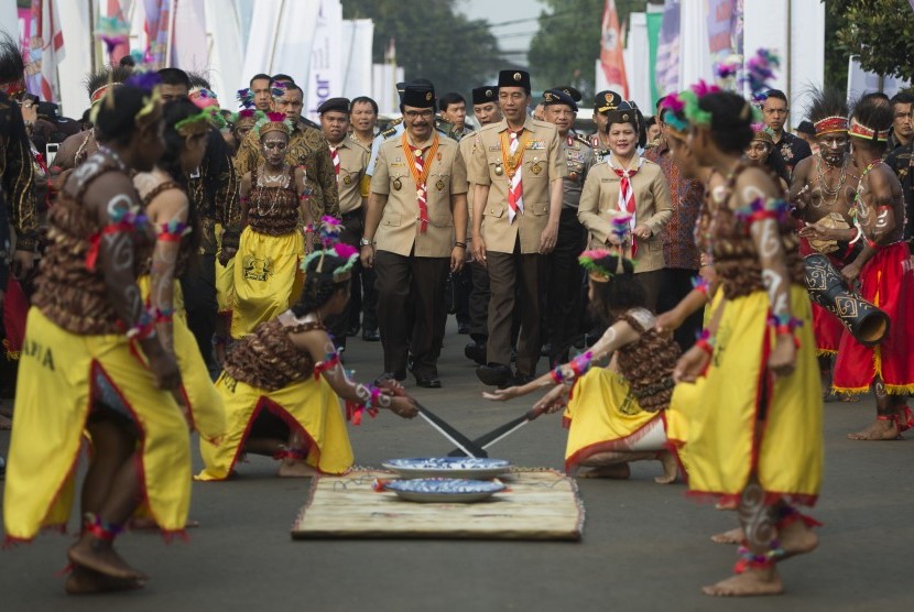 Presiden Joko Widodo (tengah) berjalan bersama Ibu Negara Iriana Joko Widodo (kanan) dan Ketua Kwartir Nasional Gerakan Pramuka Adhyaksa Dault (kiri) mengikuti prosesi Raimuna Nasional XI yang bertepatan dengan peringatan ulang tahun Pramuka ke-56 di, Bumi Perkemahan Cibubur, Jakarta, Senin (14/8).