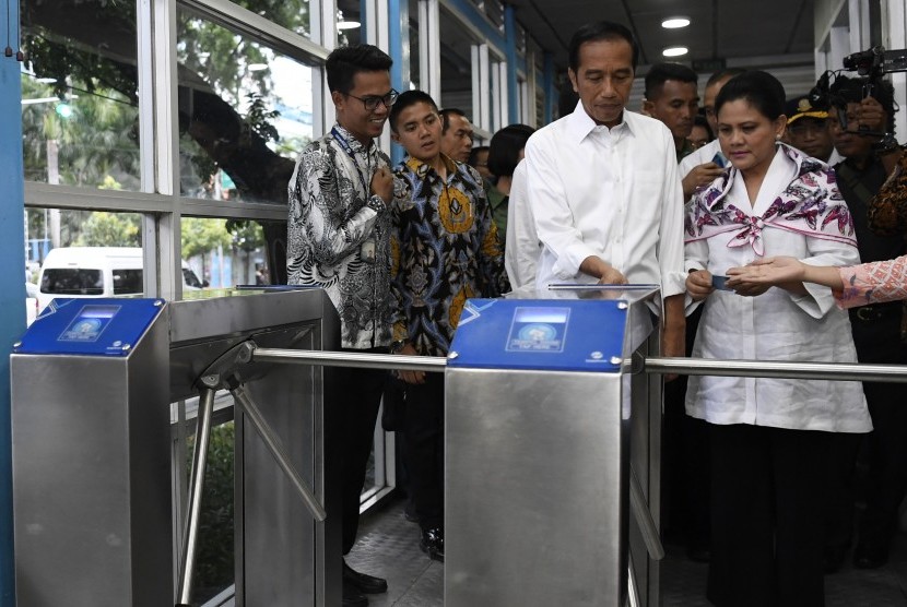 Presiden Joko Widodo (tengah) bersama Ibu Negara Iriana Joko Widodo (kanan) bersiap menaiki bus Transjakarta menuju Stasiun MRT Bundaran Hotel Indonesia di Jakarta, Kamis (21/3/2019).