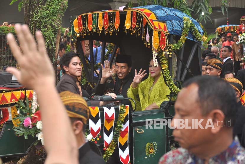Presiden Joko Widodo (tengah) dan Ibu Negara Iriana Joko Widodo (kanan) bersama putra bungsu Kaesang Pangarep (kiri) berada di dalam kereta kencana saat Kirab Kereta Kencana Pengantin melintas di Jalan Gagak Hitam, di Medan, Sumatra Utara, Ahad (26/11). 