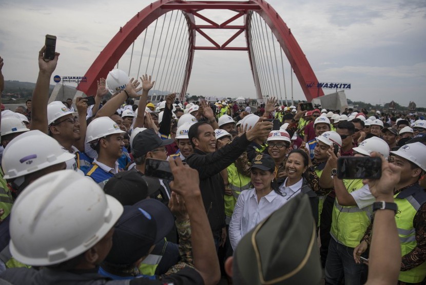 Presiden Joko Widodo (tengah) didampingi Ibu Negara Iriana Joko Widodo, Menteri BUMN Rini Soemarno bersama para pekerja proyek berswafoto usai meresmikan pengoperasian tujuh ruas jalan tol Trans Jawa di Jembatan Kalikuto, Kendal, Jawa Tengah, pada 20 Desember 2018. 