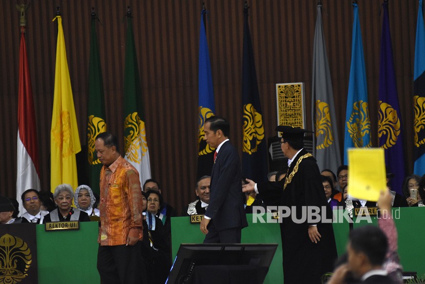 A student activist (sit, right) gives President Joko Widodo (center) a yellow card at the 68th anniversary of University of Indonesia, Depok, West Java, on Friday (Feb 2). 