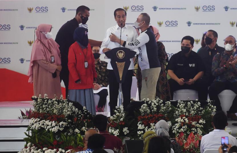 Presiden Joko Widodo (tengah) dipeluk oleh seorang pelaku usaha mikro saat acara pemberian Nomor Induk Berusaha (NIB) pelaku Usaha Mikro Kecil (UMK) perseorangan tahun 2022 di Jakarta, Rabu (13/7/2022). Presiden memberikan Nomor Induk Berusaha (NIB) kepada 2.500 pelaku UMK dari Provinsi DKI Jakarta dan sekitarnya.
