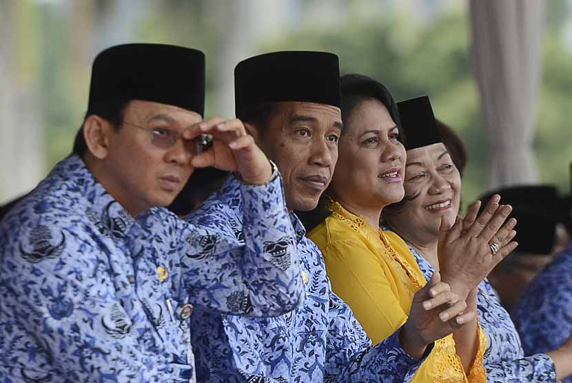 Presiden Joko Widodo (tengah) duduk bersama Gubernur DKI Basuki Tjahaja Purnama (kiri) saat upacara HUT Korps Pegawai Republik Indonesia (Korpri) ke-43 di lapangan Silang Monas, Jakarta, Senin (1/12).  