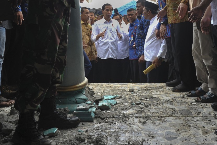 Presiden Joko Widodo (tengah) melihat kondisi bangunan Masjid Atta Darut yang rusa berat di Pidie Jaya, Aceh, Jumat (9/12).