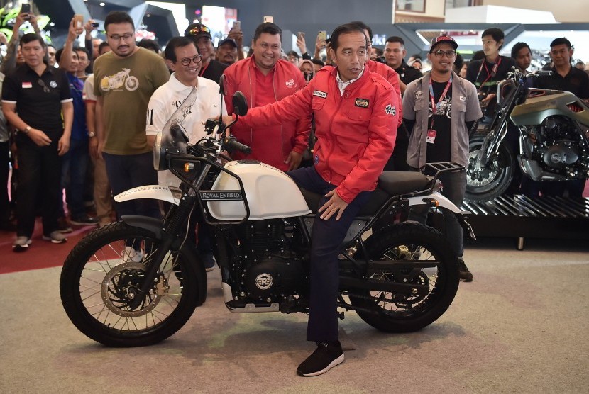 Presiden Joko Widodo (tengah) mencoba motor Royal Enfield saat mengunjungi Indonesia Motorcycle Show (IMOS) 2018 di Jakarta Convention Center, Jakarta, Sabtu (3/11/2018). 