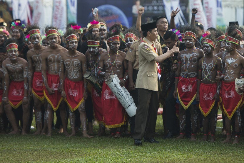 Presiden Joko Widodo (tengah) mengacungkan jempol usai berfoto bersama para anggota pramuka berkostum tradisional Papua dalam acara Raimuna Nasional XI yang bertepatan dengan peringatan ulang tahun Pramuka ke-56 di, Bumi Perkemahan Cibubur, Jakarta, Senin (14/8). 