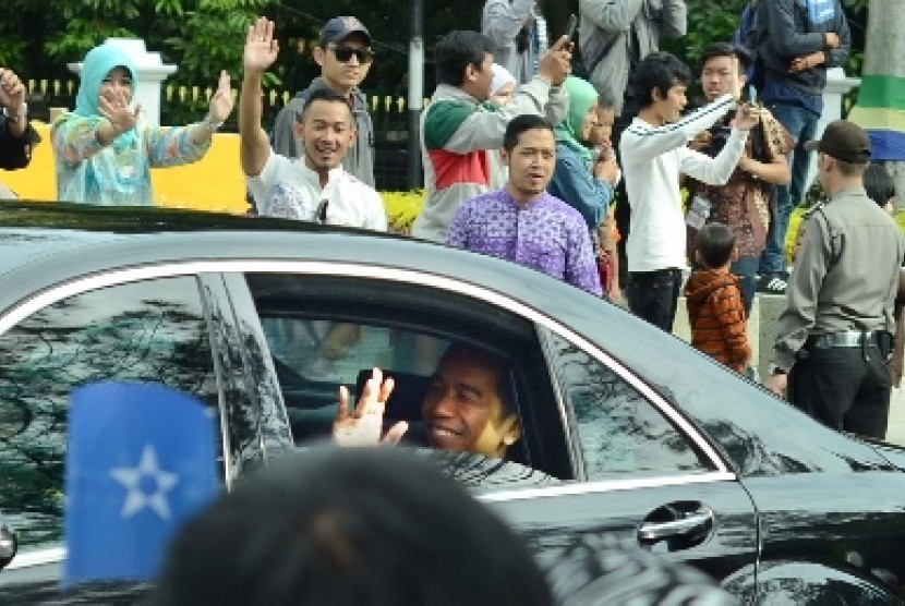 Presiden Jokowi melambaikan tangan kepada warga saat menuju tempat Konferensi Asia Afrika (KAA) ke-60, di Gedung Merdeka, Bandung, Jumat (24/4).