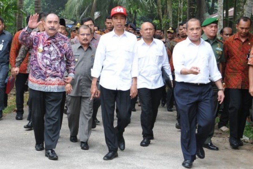 Presiden Jokowi (tengah) berjalan bersama Menteri Desa Marwan Jafar (ketiga kanan) usai melakukan peletakan batu pertama pembangunan sejumlah infrastruktur di Nagari Parit Malintang, Kecamatan Enam Lingkung, Kabupaten Padang Pariaman, Kamis (8/10).