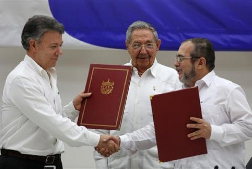 Presiden Kolombia Juan Manuel Santos (kiri) dan Komandan Pasukan Bersenjata Revolusi Kolombia (FARC) Timoleon Jimenez (kanan) berjabat tangan saat menandatangani perjanjian damai di Havana, Kuba, Kamis, 23 Juni 2016. Di tengah adalah Presiden Kuba Raul Cas