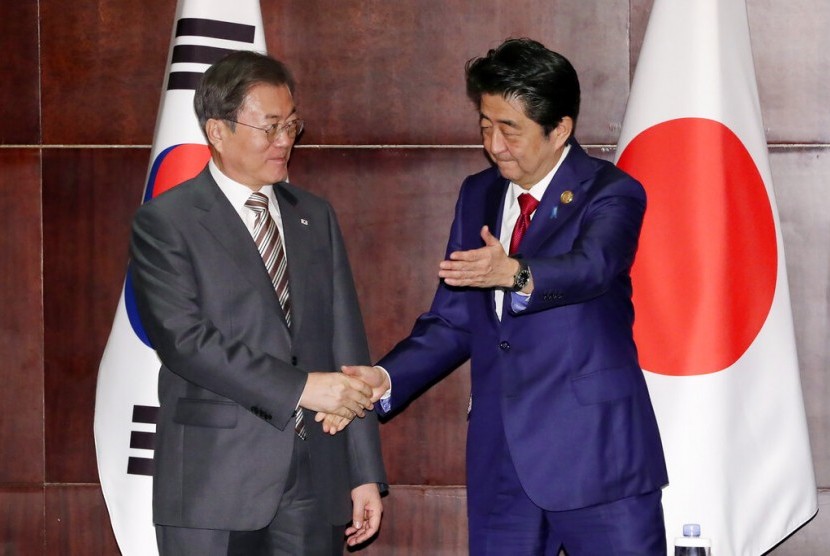 Presiden Korea Selatan (Korsel) Moon Jae-in (kiri) bersalaman dengan Perdana Menteri Jepang Shinzo Abe. Korea Selatan dan Jepang pada Kamis (25/5/2023) menggelar dialog pertama tentang energi dalam enam tahun 