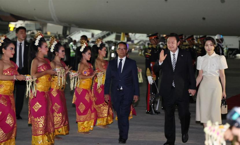  Presiden Korea Selatan Yoon Suk-yeol (2-kanan), ditemani oleh istrinya, Kim Keon-hee, melambaikan tangan saat ia tiba untuk menghadiri pertemuan puncak tahunan ekonomi utama G20, di Bandara Internasional Ngurah Rai di Bali, Indonesia, 14 November 2022. 