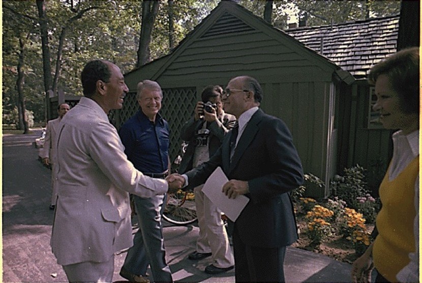 Presiden Mesir Anwar Sadat bersalaman dengan PM Israel Menachem Begin disaksikan Presiden AS Jimmy Carter di rumah peristirahatan presiden AS, Camp David 