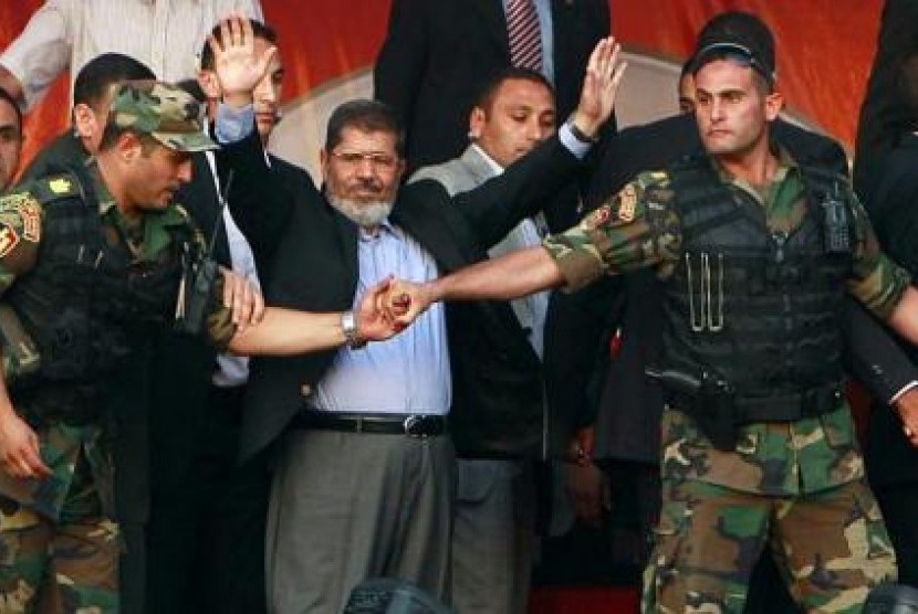 Presiden Mesir, Mohammed Mursi melambai ke arah pendukungnya. Demonstrasi yang kian panas akibat dekrit presiden pada 22 November lalu memaksa Mursi mengungsi, pergi meninggalkan istana kepresidenan.