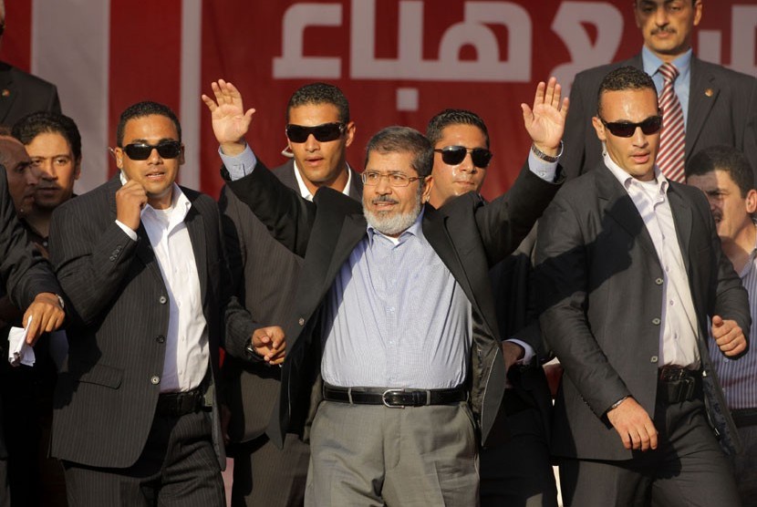  Presiden Mesir terpilih Muhammad Mursi melambaikan tangan pada puluhan ribu pendukungnya yang berkumpul di Tahrir Square, Kairo.   (Amr Nabil/AP)