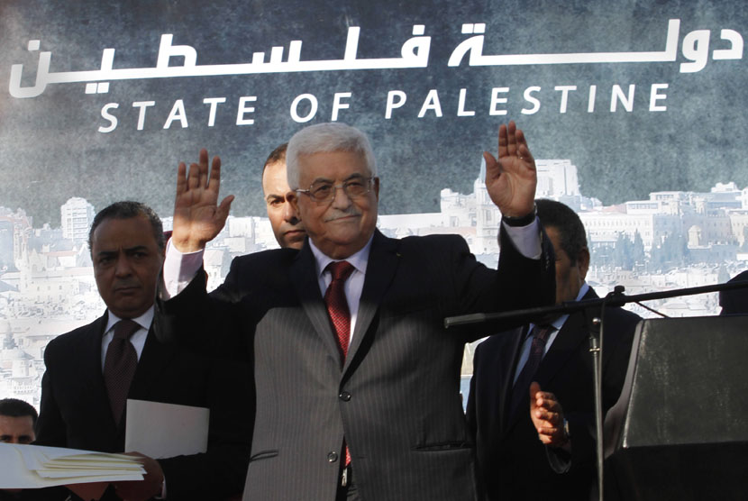   Presiden Palestina Mahmoud Abbas melambaikan tangan ke kerumunan warga saat merayakan pengakuan negara Palestina oleh PBB di Ramallah,Ahad (2/12).  (AP/Nasser Shiyoukhi)