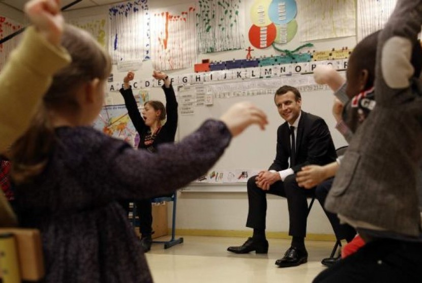 Presiden Prancis Emmanuel Macron ketika mengunjungi anak-anak usia dini di Paris.  
