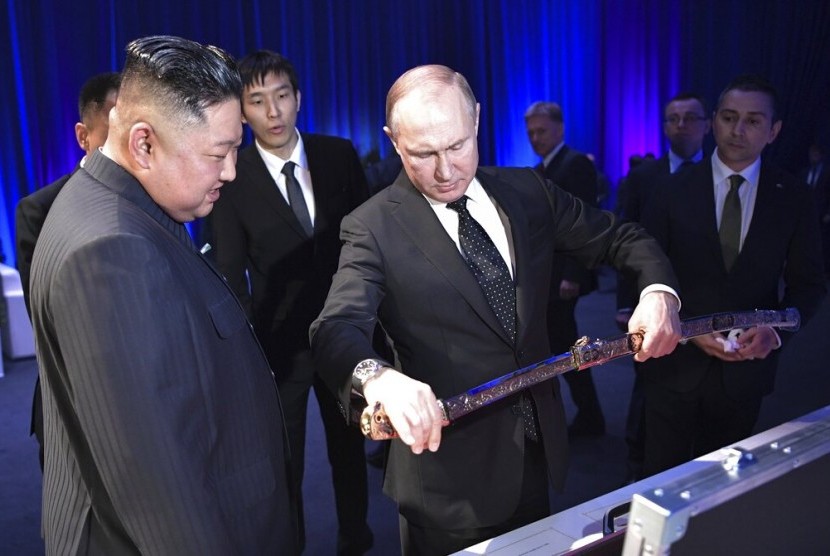Presiden Rusia Vladimir Putin (kanan) memperlihatkan sebilah pedang Rusia sebagai hadiah kepada Pemimpin Korea Utara (Korut) Kim Jong-un di Vladivostok, Rusia, Kamis (25/4). Putin mengatakan hubungan yang lebih erat akan menjadi kepentingan kedua negara.