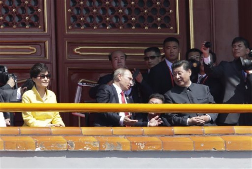 Presiden Rusia Vladimir Putin (tengah) berbincang dengan Presiden Cina Xi Jinping (kanan). Tampak Presiden Korsel Park Geun-hye duduk di kiri di Gerbang Tiananmen menyaksikan parade militer memperingati 70 tahun kekalahan Jepang dalam Perang Dunia II, Kami