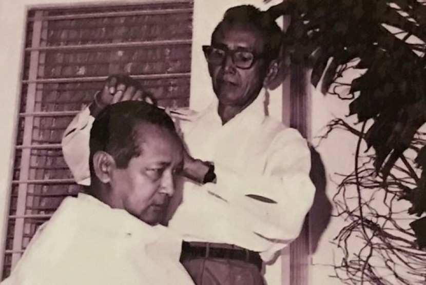 Presiden Soeharto sedang mencukur rambut di rumahnya. 