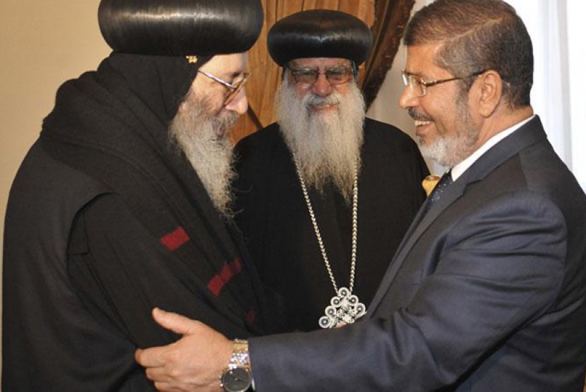 Presiden Terpilih Mesir Mohammed Mursi menyalami uskup Koptik, Beshoy (kiri) di istana kepresidenan di Kairo, Rabu (27/6)