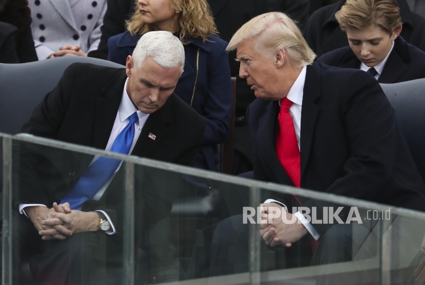 President Donald Trump leans over to talk with Vice President Mike Pence.