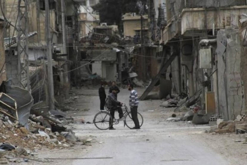 Pria berbincang di dekat bangunan rusak yang menurut para aktivis akibat pengeboman yang dilakukan oleh pasukan Presiden Bashar Al Assad di Daraya, dekat Damaskus, dalam foto 2 Februari 2014. 