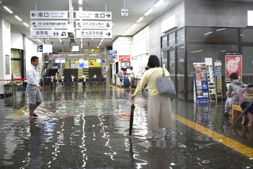 Pria berjalan melalui kawasan yang banjir di stasiun kereta di Saga, selatan Jepang, Rabu (28/8). Prefektur Saga diguyur hujan lebat sejak Rabu pagi.