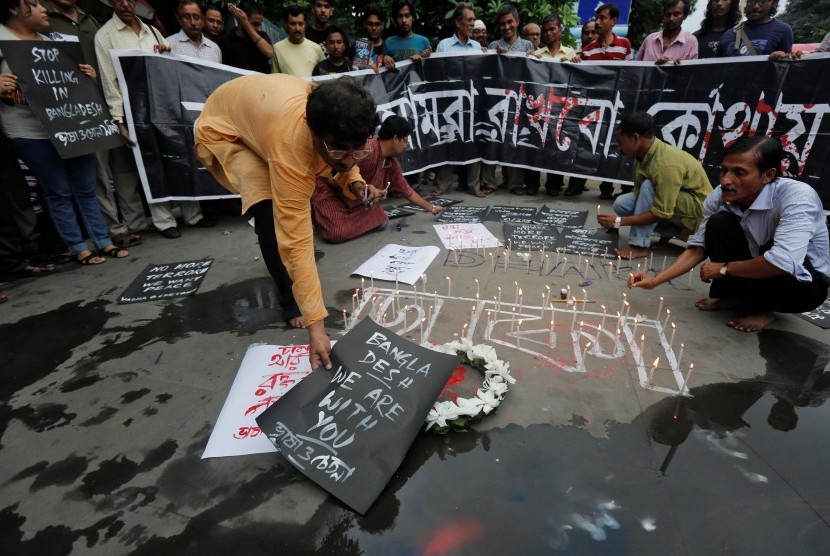 Pria meletakkan ucapan dan menyalakan lilin mengenang korban tewas akibat teror di sebuah restoran di Dhaka, Bangladesh, Sabtu (2/7).